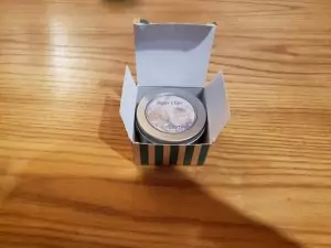 Opening the box reveals a circular metal container