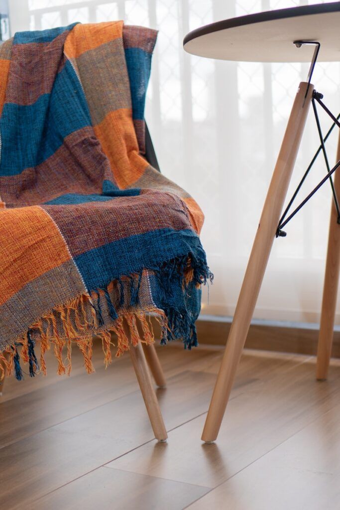 A chair with a colorful blanket on it next to a table