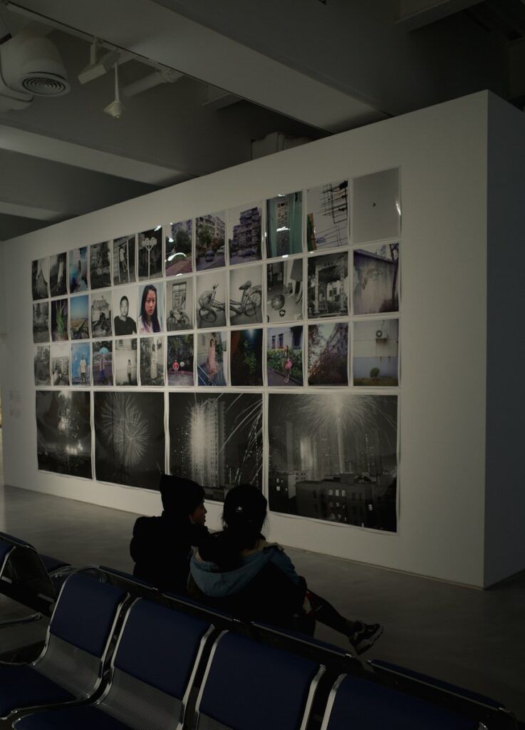 People admire photos on a gallery wall.