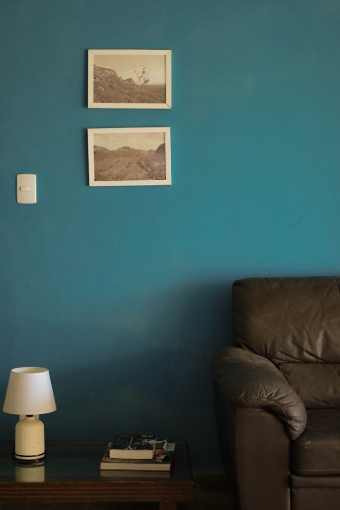 a living room with a brown leather couch and two pictures on the wall