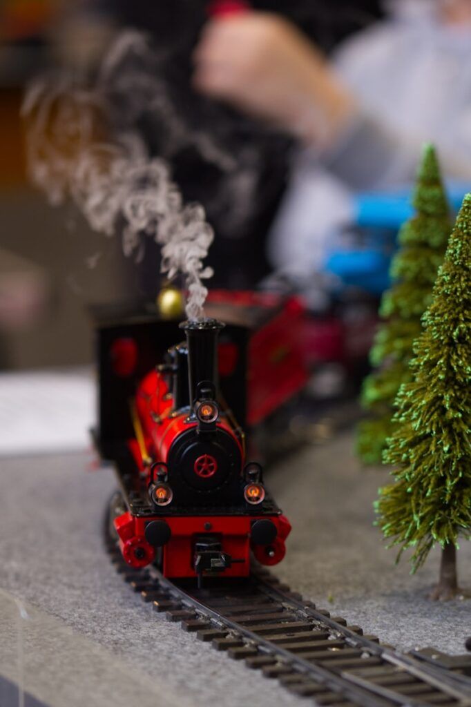 A red toy train with smoke on tracks