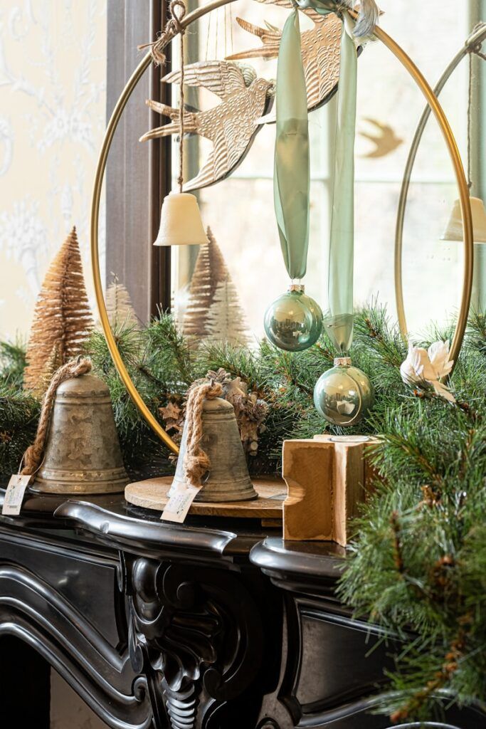a mantle decorated with christmas garland decorations and bells