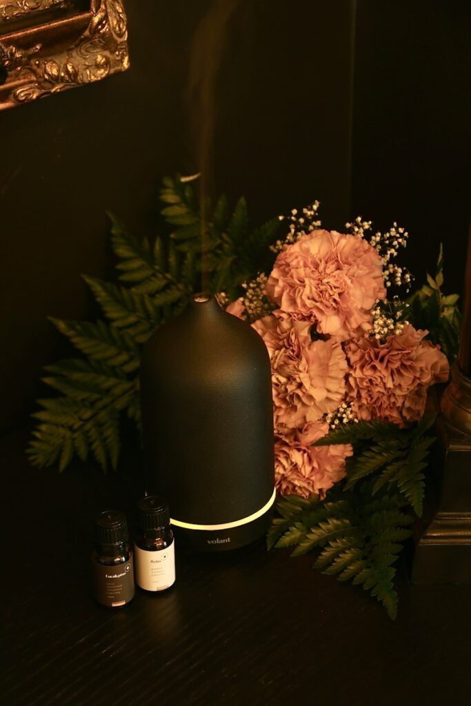 a black diffuser sitting on top of a table next to flowers