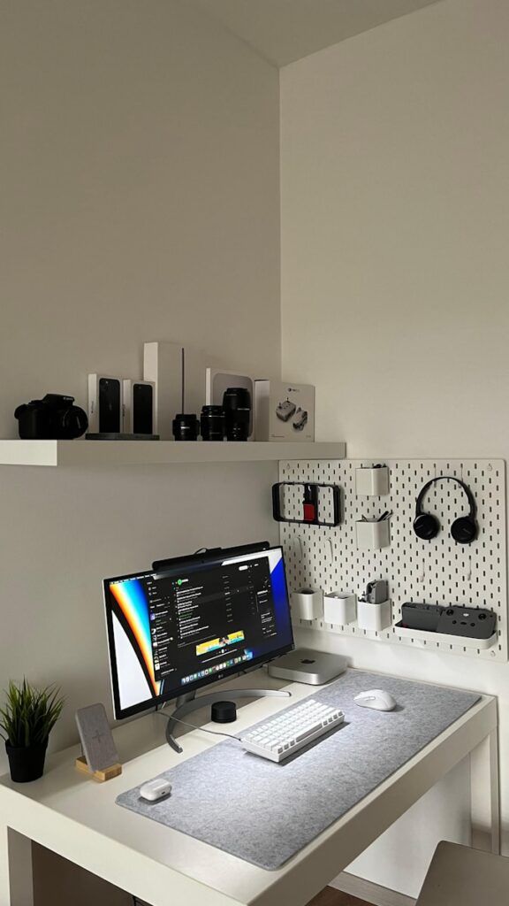 a white desk with a computer on top of it. Compact corner desk setup.