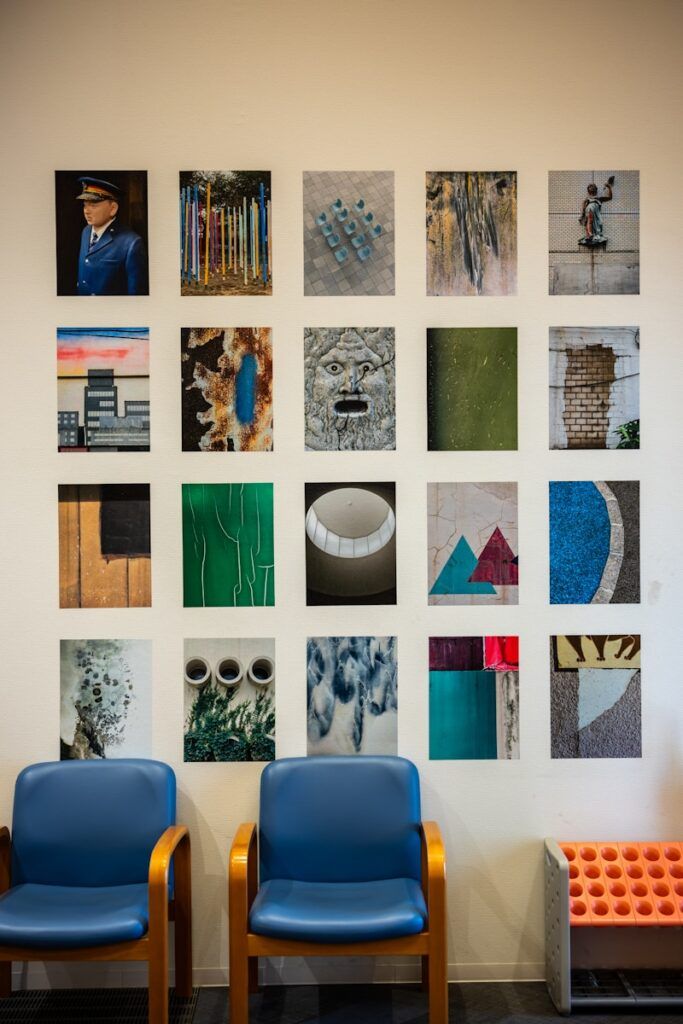 Twenty framed artworks displayed on a white wall.