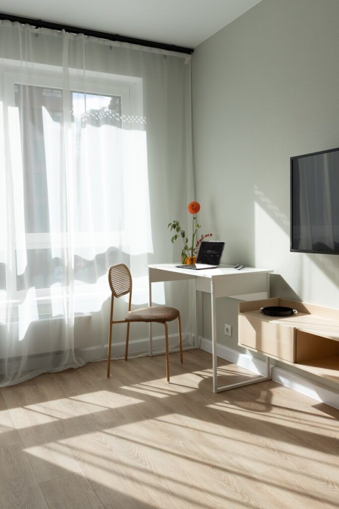 Sunlit room with a desk, chair, and television.