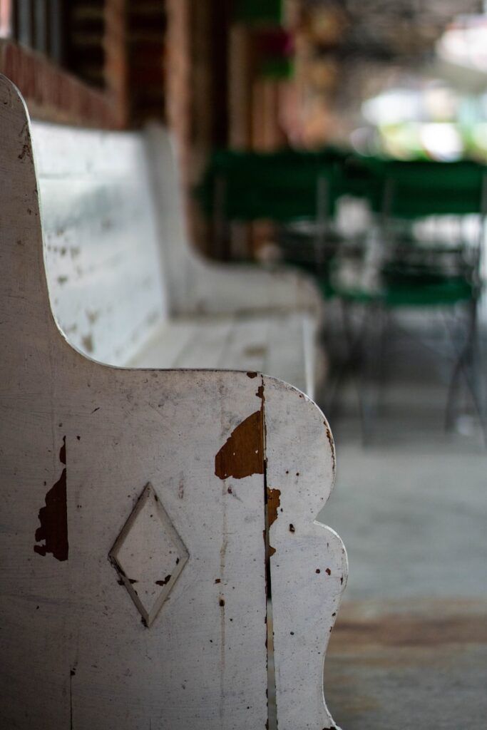 a close up of a white bench with a green table in the background