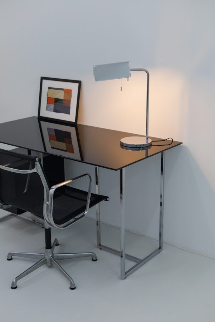 A desk with a chair and a lamp on it