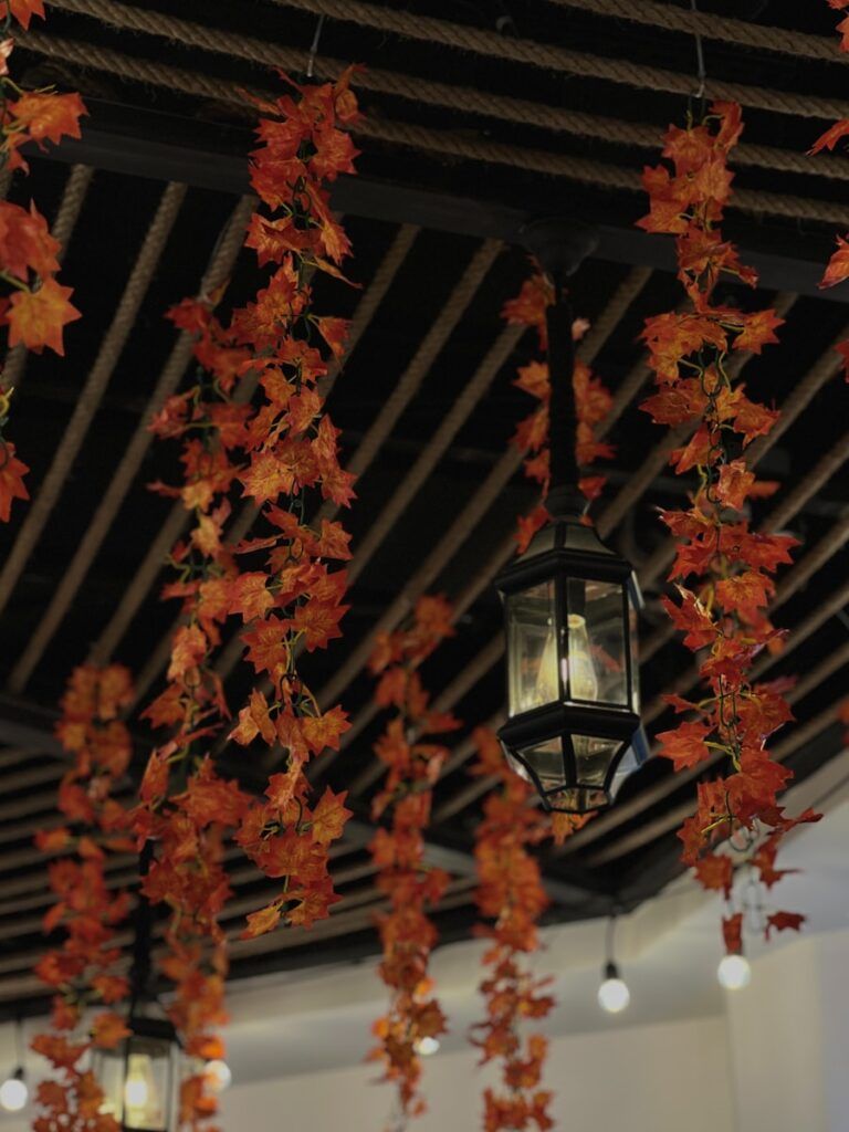 Hanging artificial autumn leaves and lanterns indoors
