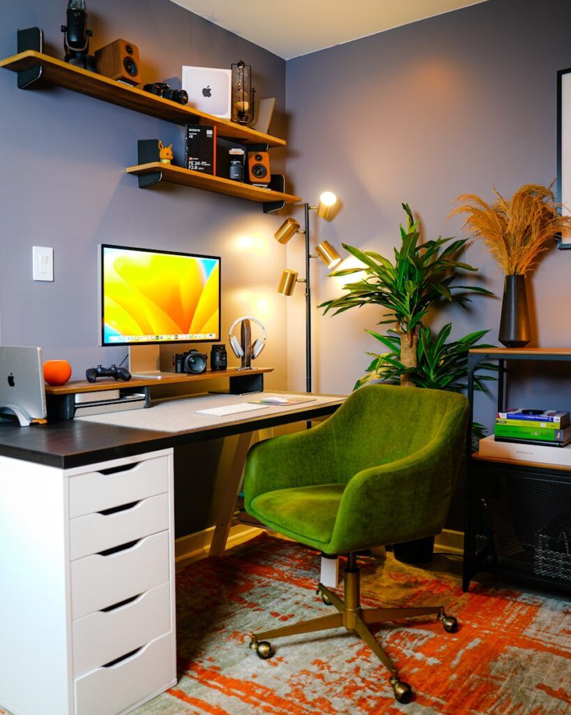 a desk with a computer and a green chair