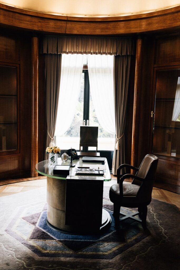 Elegant office with desk, chair, and large window.