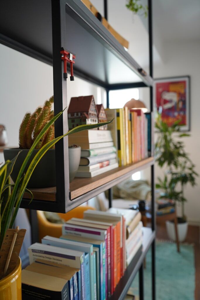 a bookshelf filled with lots of books next to a potted plant