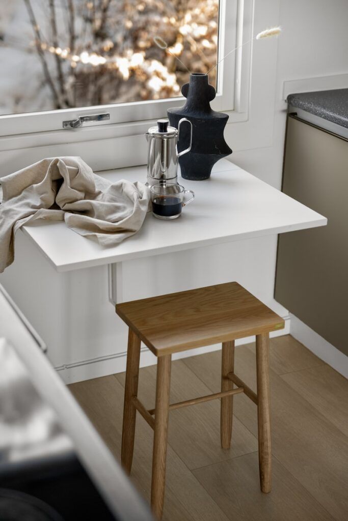 A kitchen with a window and a table with a coffee pot on it