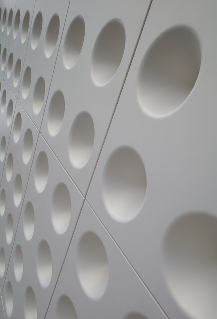 A white wall features numerous circular indentations.