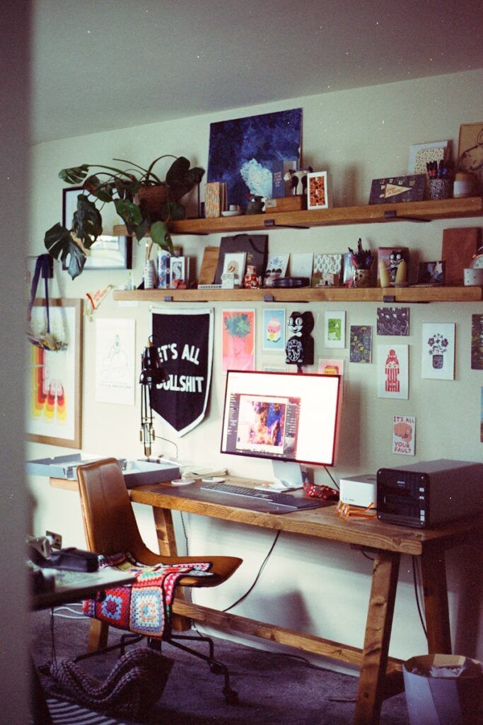A cluttered desk with a computer and art supplies.