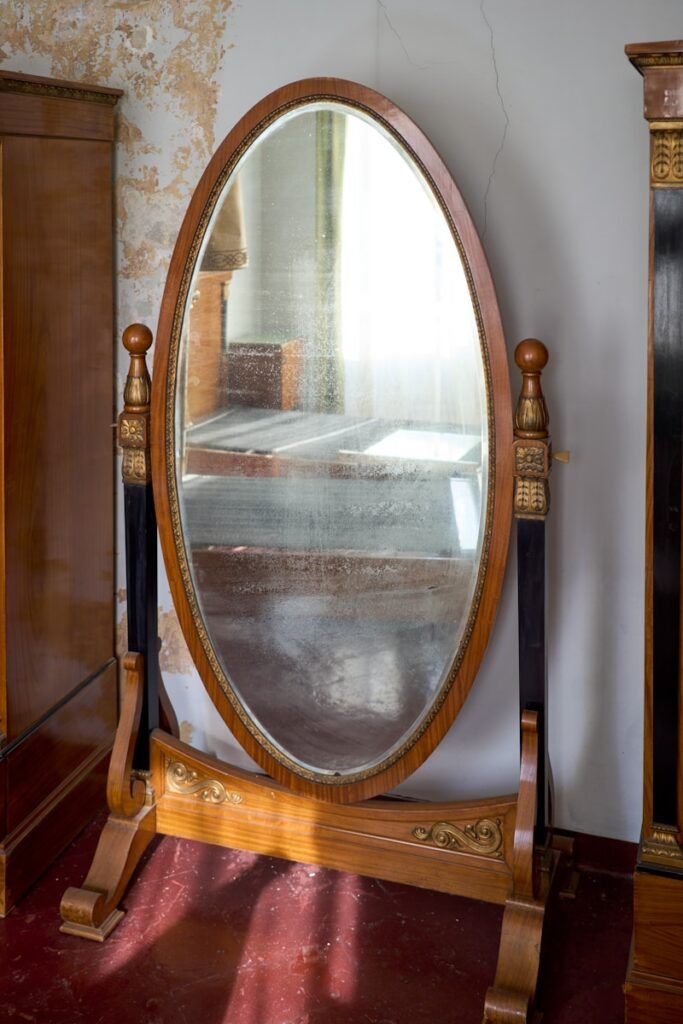 a large round mirror sitting on top of a wooden stand