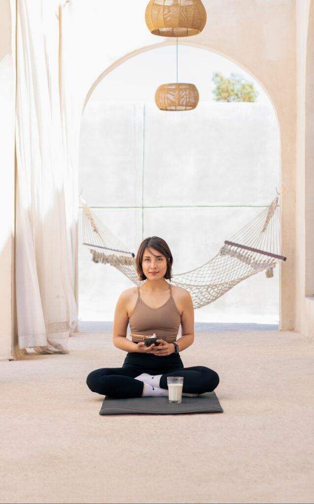 a woman sitting on a yoga mat in a hammock
