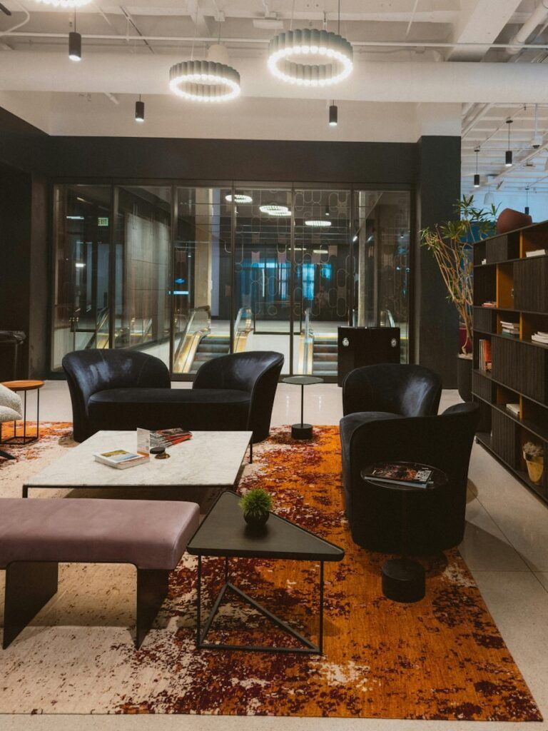 Modern lounge area with black furniture and abstract rug.