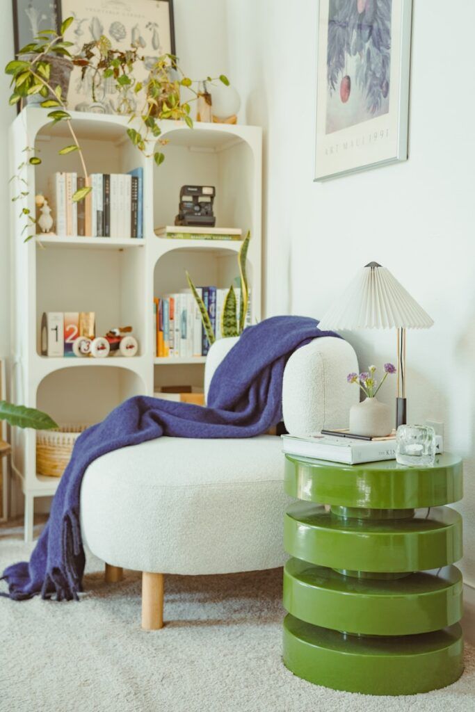 Cozy reading nook with a white chair and green table.
