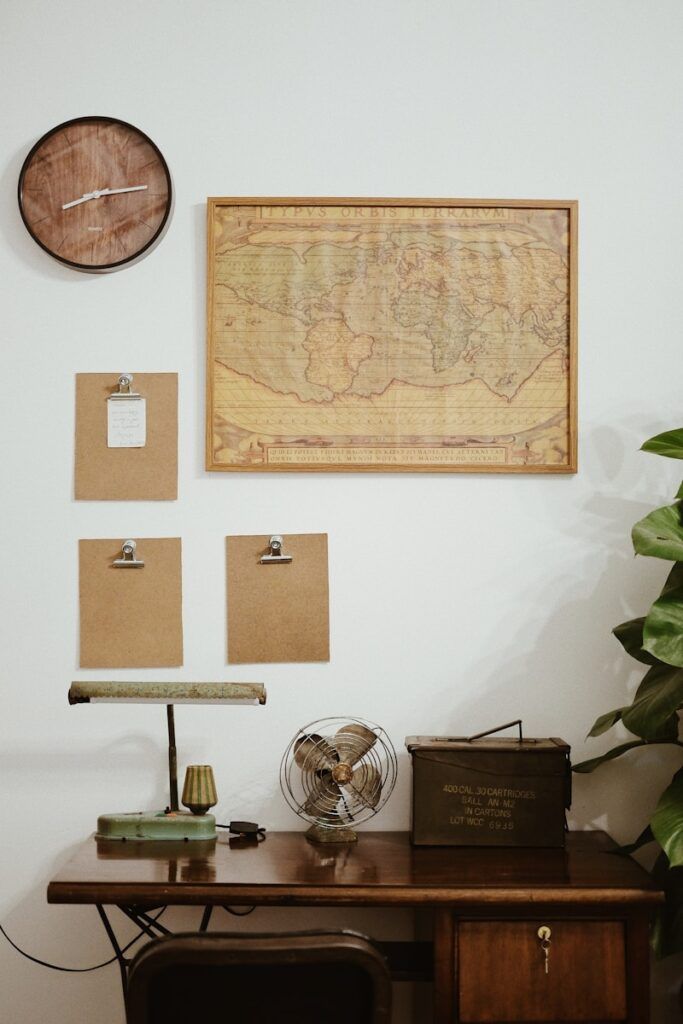 a wooden desk topped with a wooden clock next to a wall mounted map