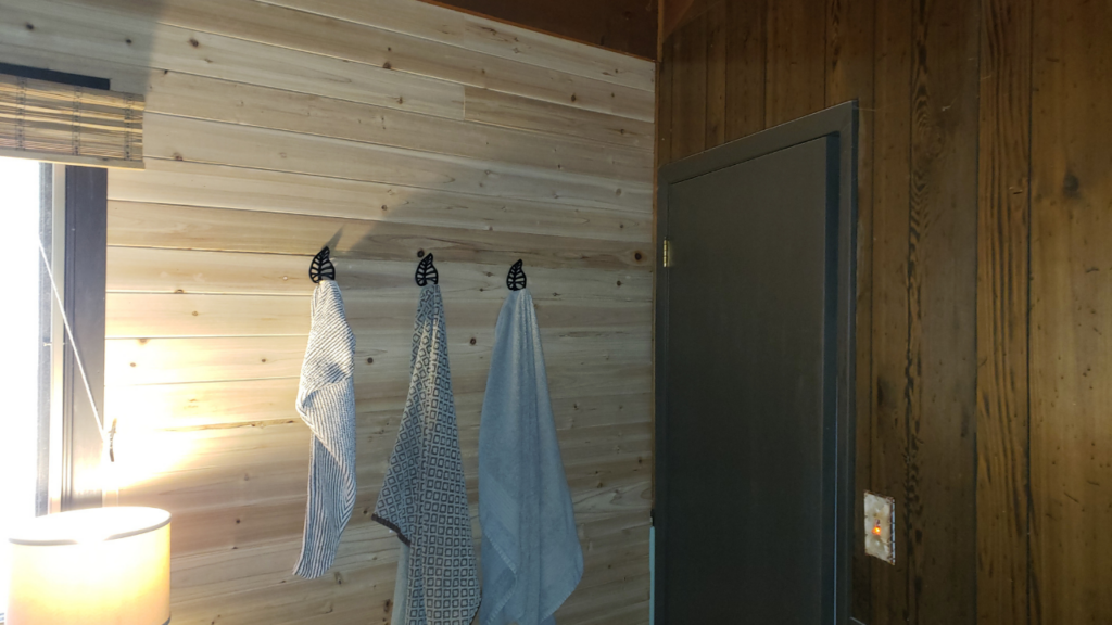 Finished cedar accent wall with black leaf-shaped towel hooks and towels
