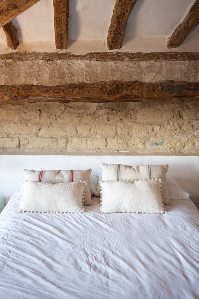 Original Beams and Textured Stone Walls in a Rustic Bedroom